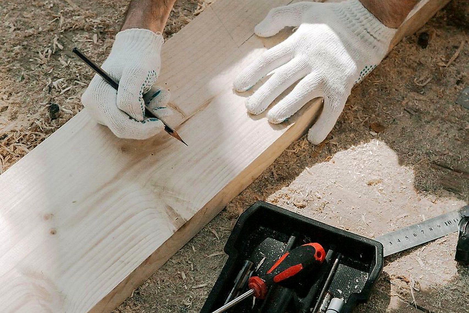 Free Carpenter measuring and marking wood plank with precision tools and gloves. Stock Photo