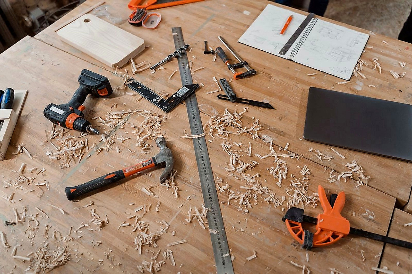 Free A workbench with various woodworking tools alongside sketches and wood shavings, indicating an active project. Stock Photo