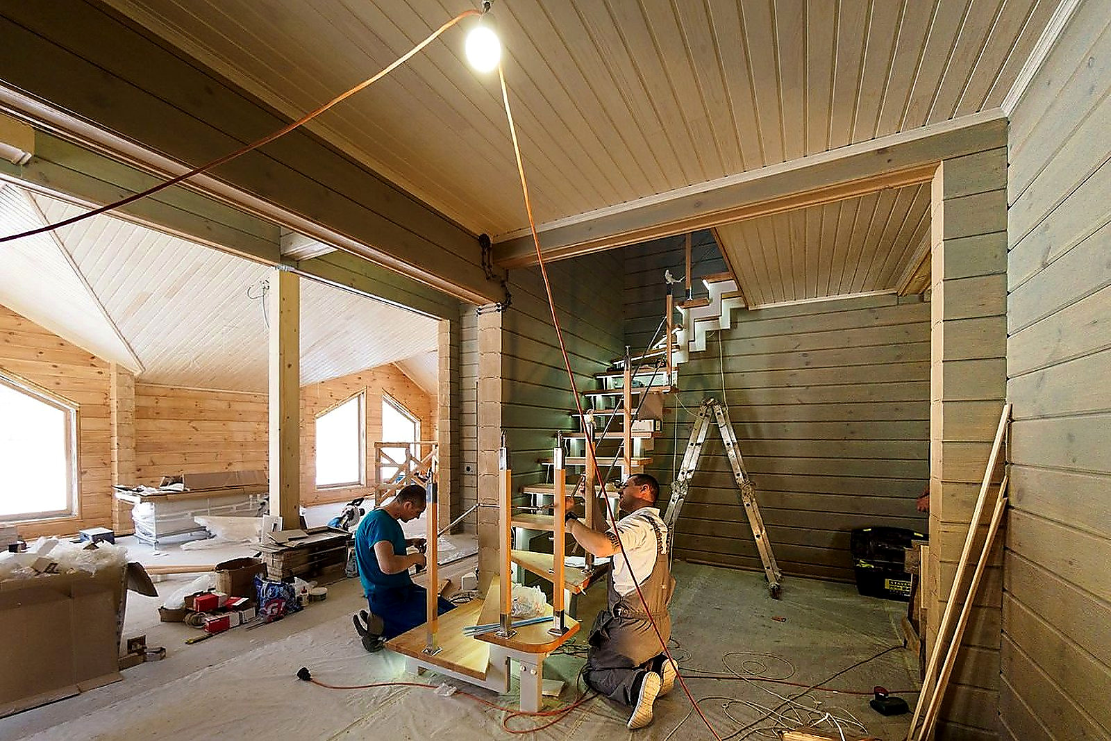 Free Carpenters skillfully assembling a modern wooden staircase inside a newly constructed home interior. Stock Photo